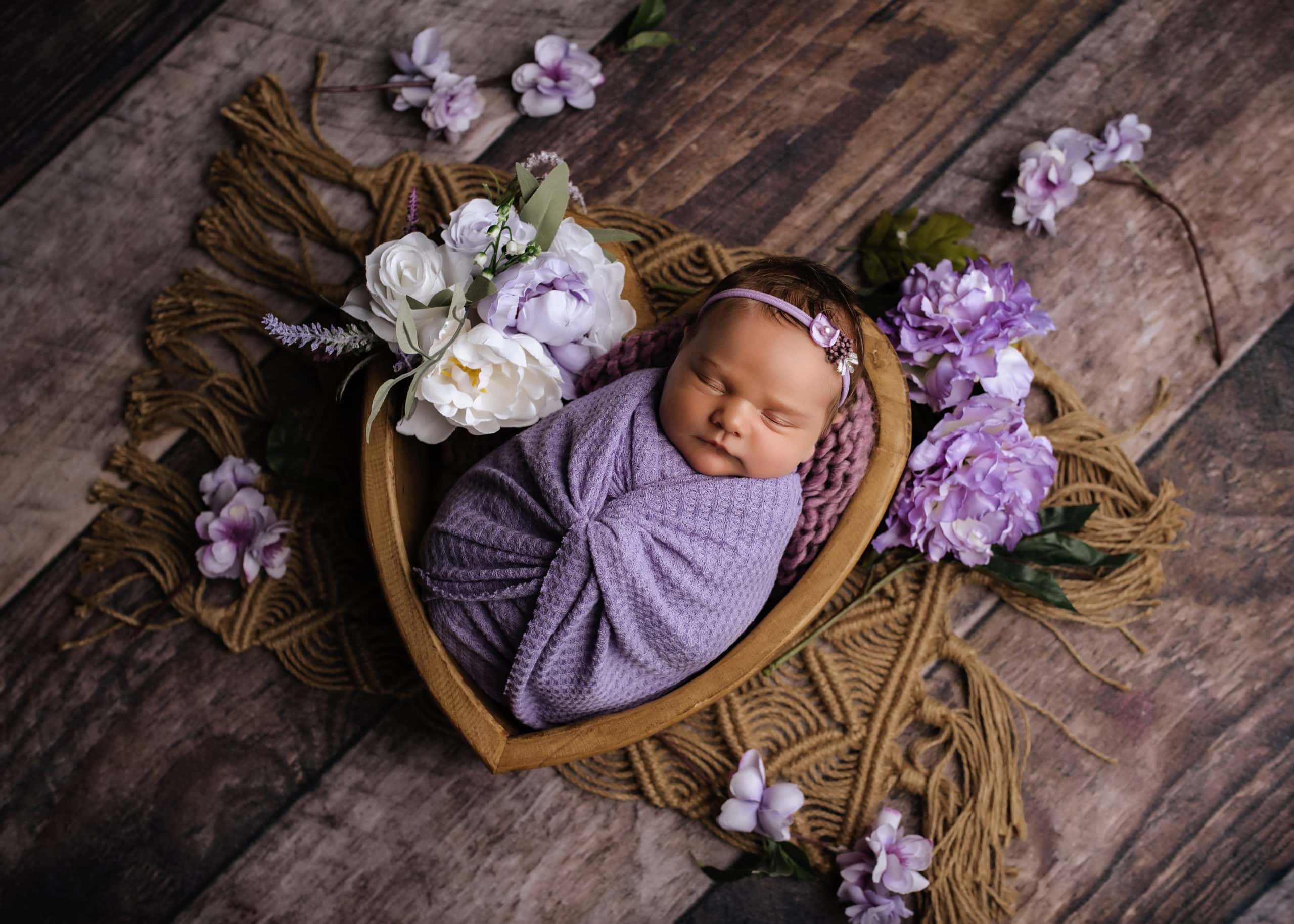 Newborn Baby in a Heart Bowl wrapped in Purple with purple Flowers, Prince George, Newborn Photography Studio