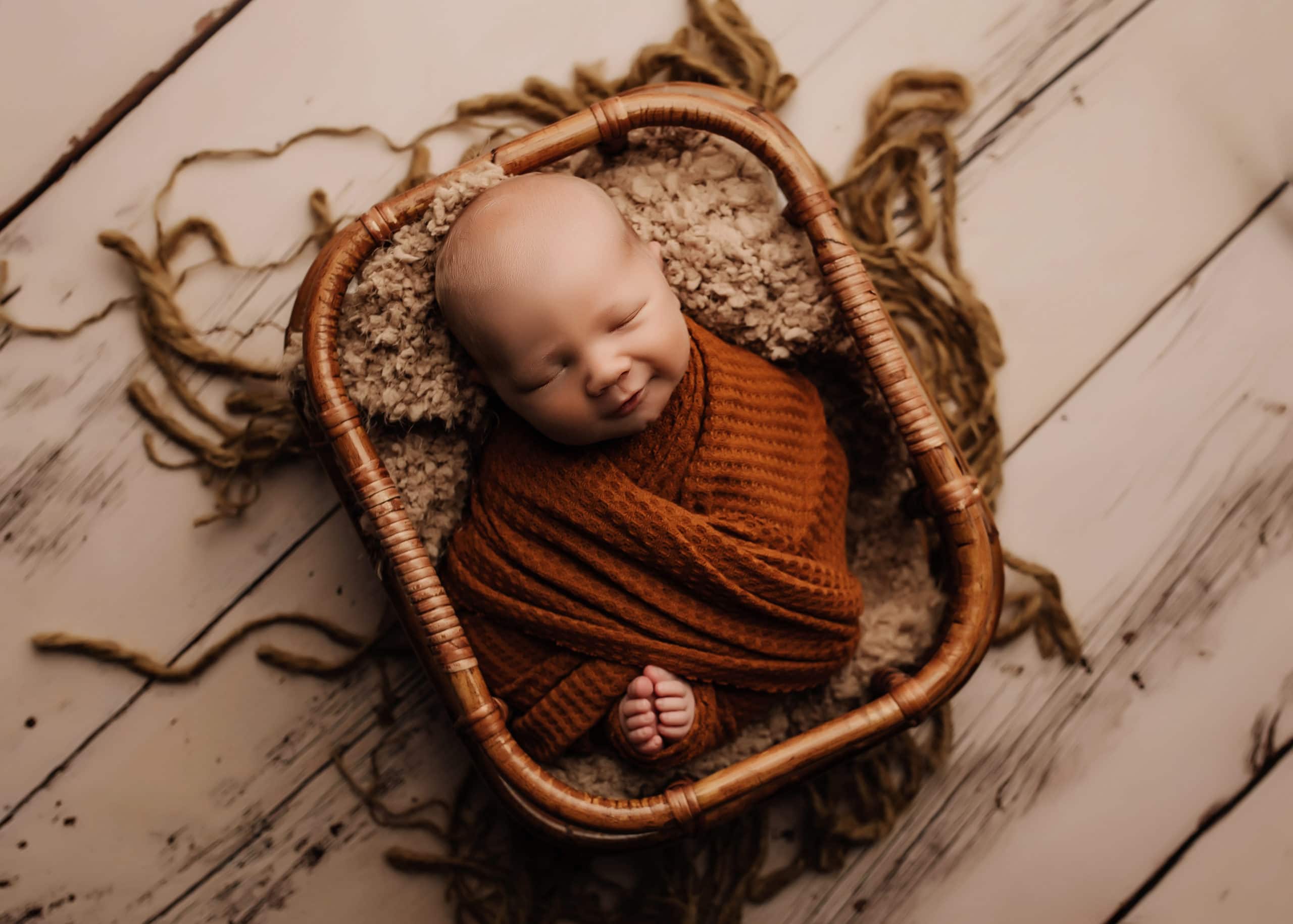 newborn baby boy wrapped in orange in a basket, prince george newborn photographer