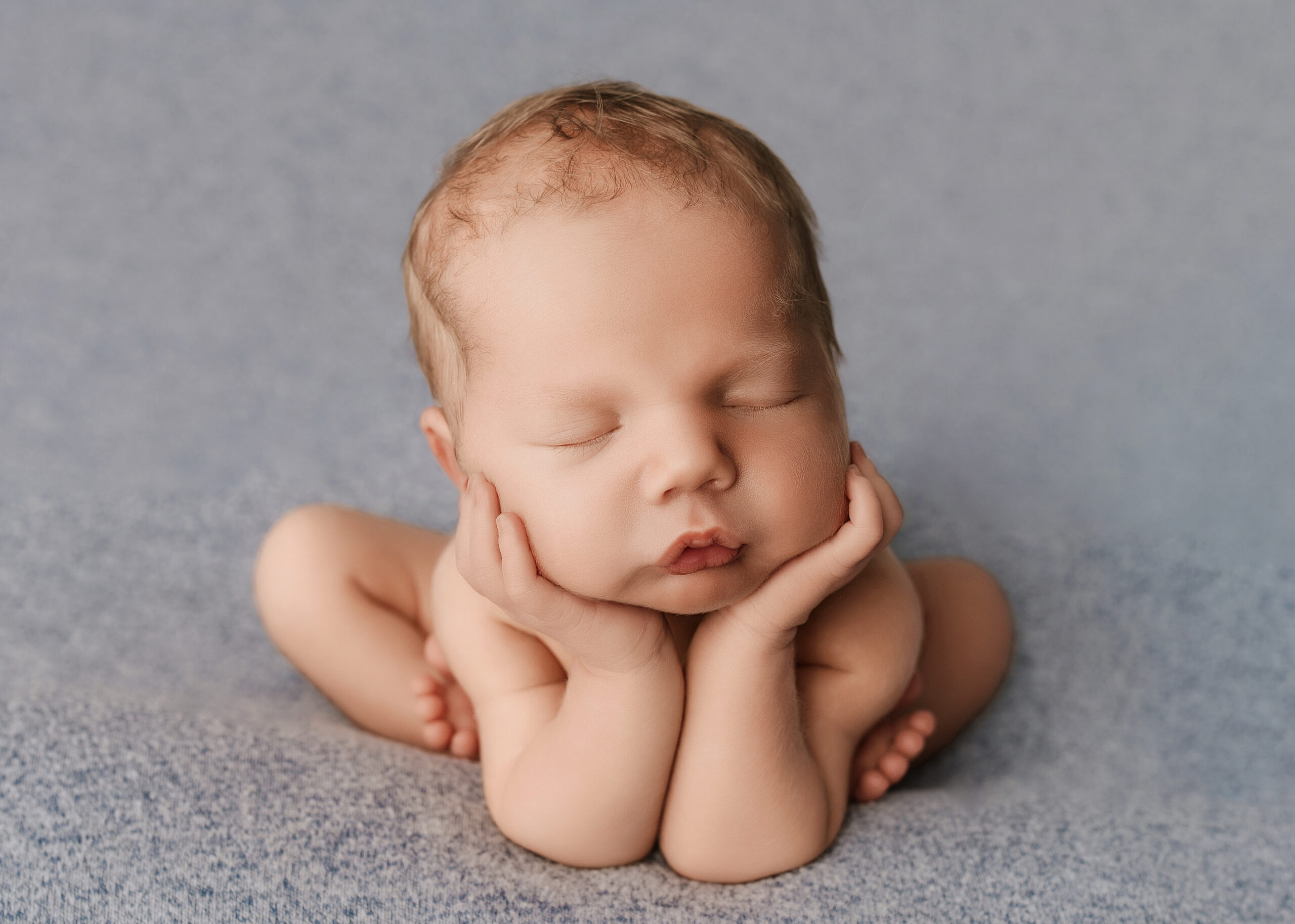 newborn baby safely posed in the froggy pose with his chin on his hands in Prince George BC