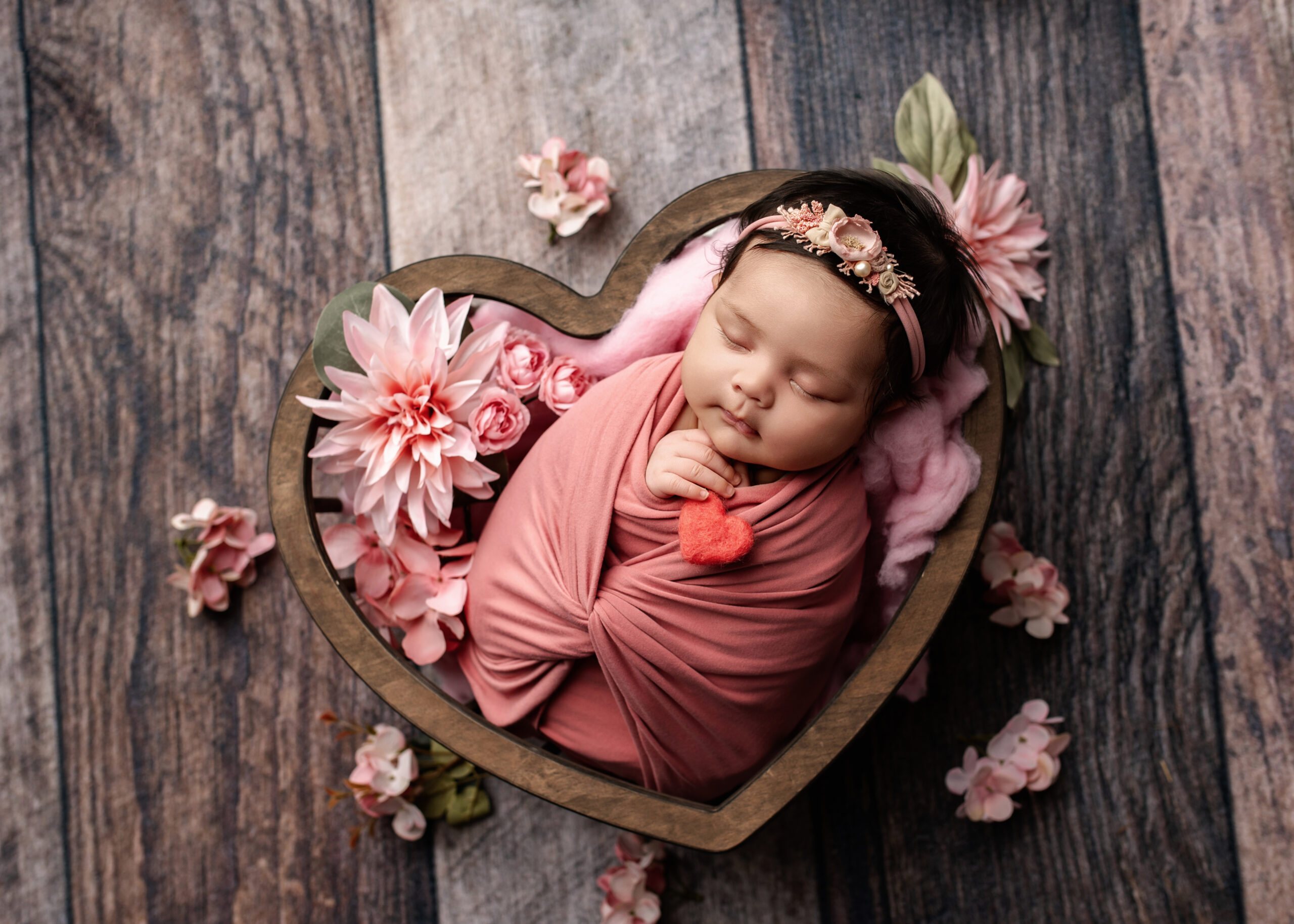 baby girl wrapped up in pink in a heart shaped bowl. lots of hair, prince george, bc, award winning photographer
